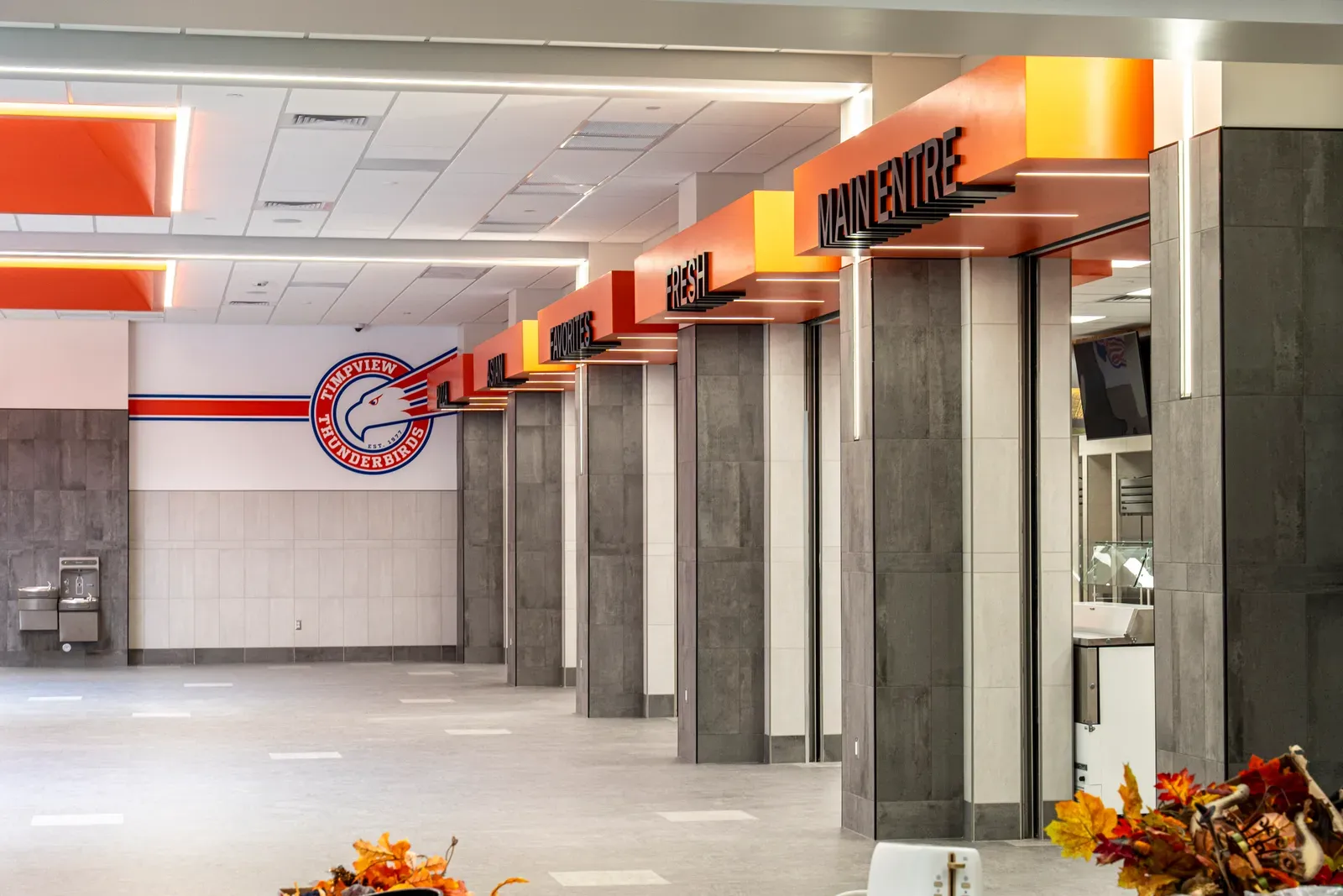 Row of cafeteria serving stations with orange signs beside a Timpview Thunderbirds logo on the wall.