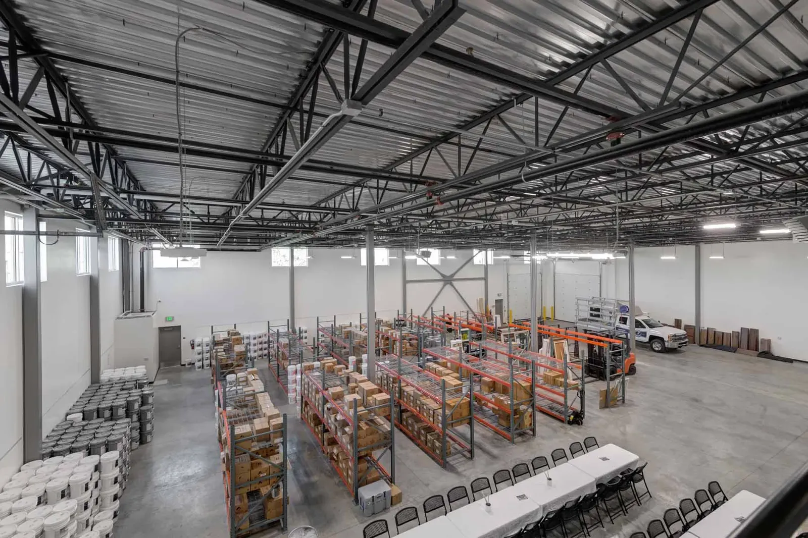 Warehouse seen from above, with orange storage racks full of boxes under exposed steel roof trusses