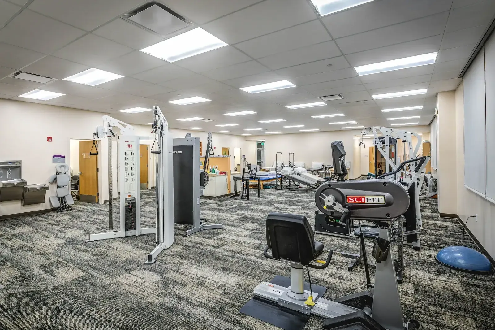Physical therapy gym with exercise machines and treatment tables