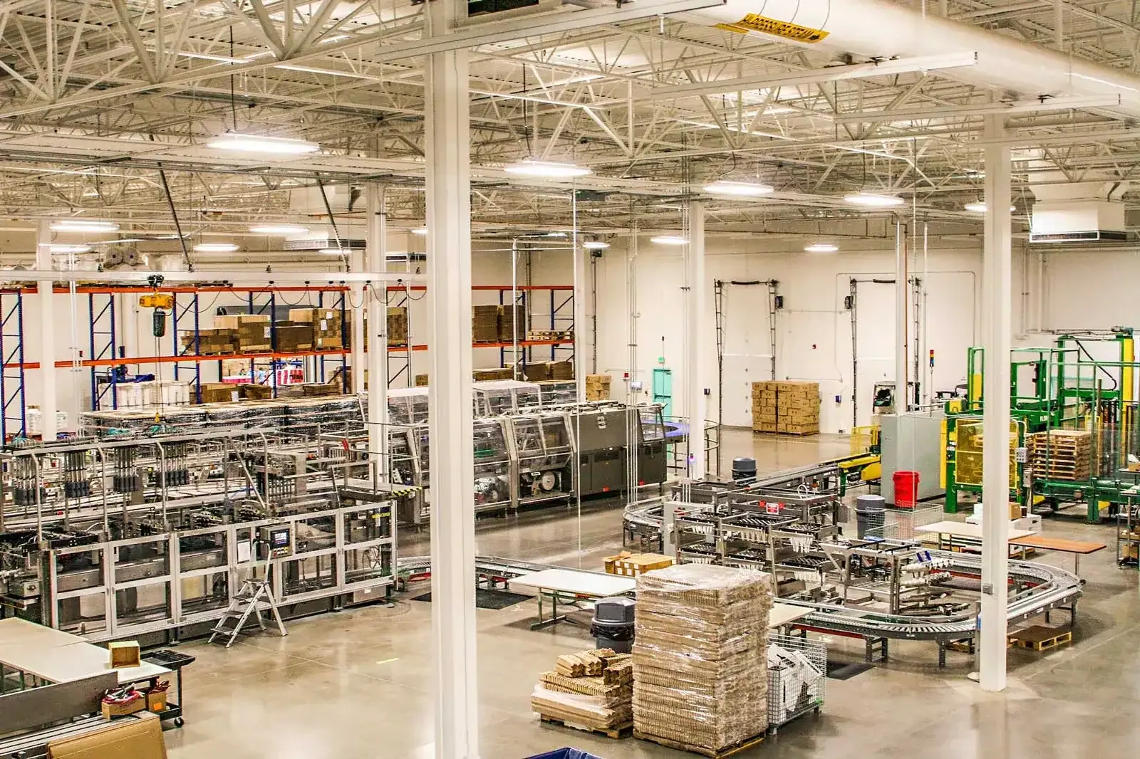 Production floor seen from above, with packaging machinery, conveyors and pallets of cartons.