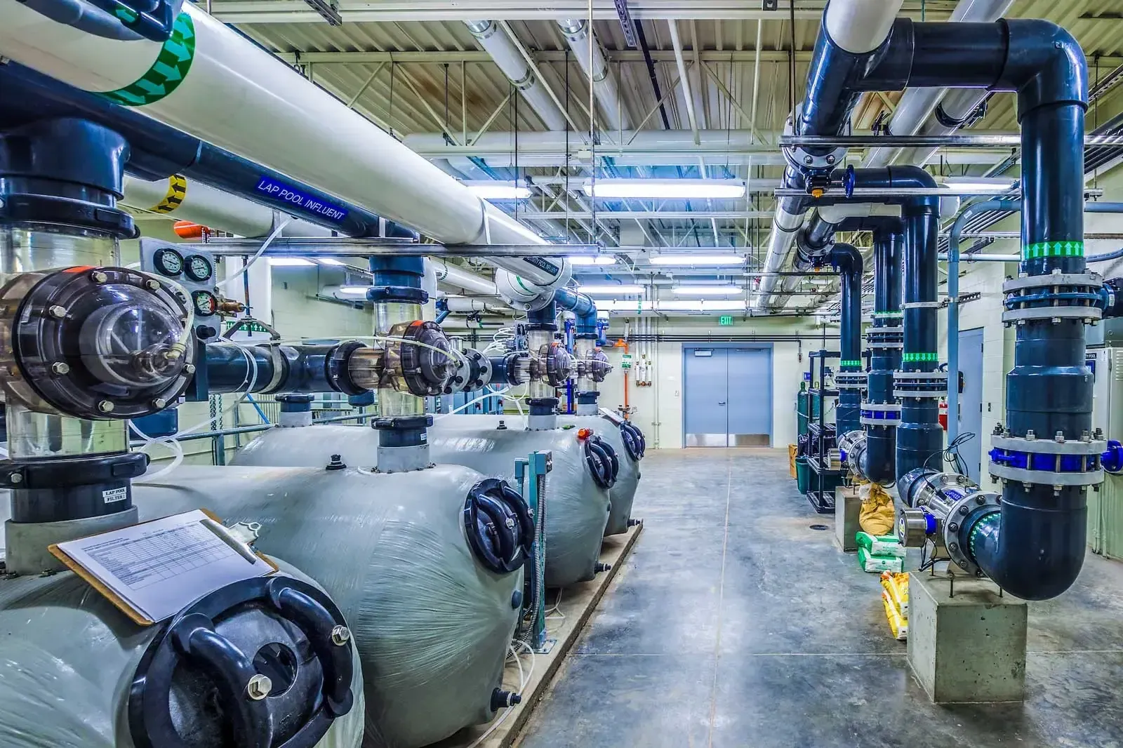 Pool mechanical room with large filter tanks and colored piping