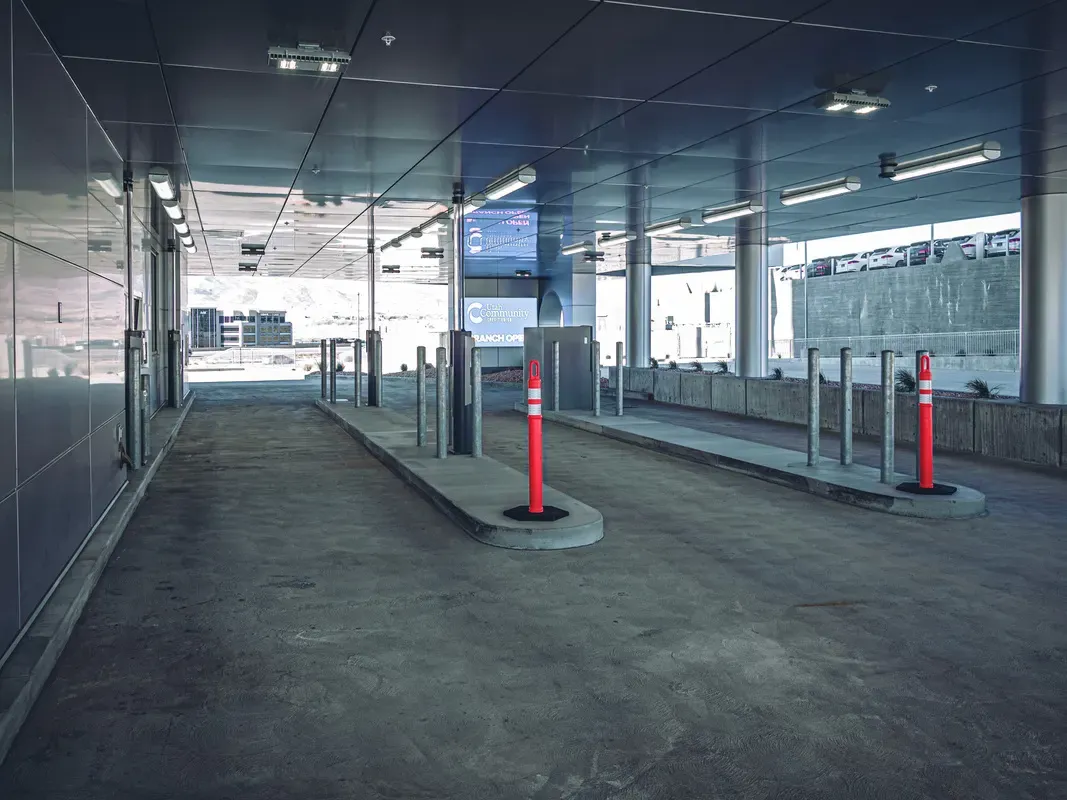 Covered drive-up lanes with traffic bollards and lighting beneath the building