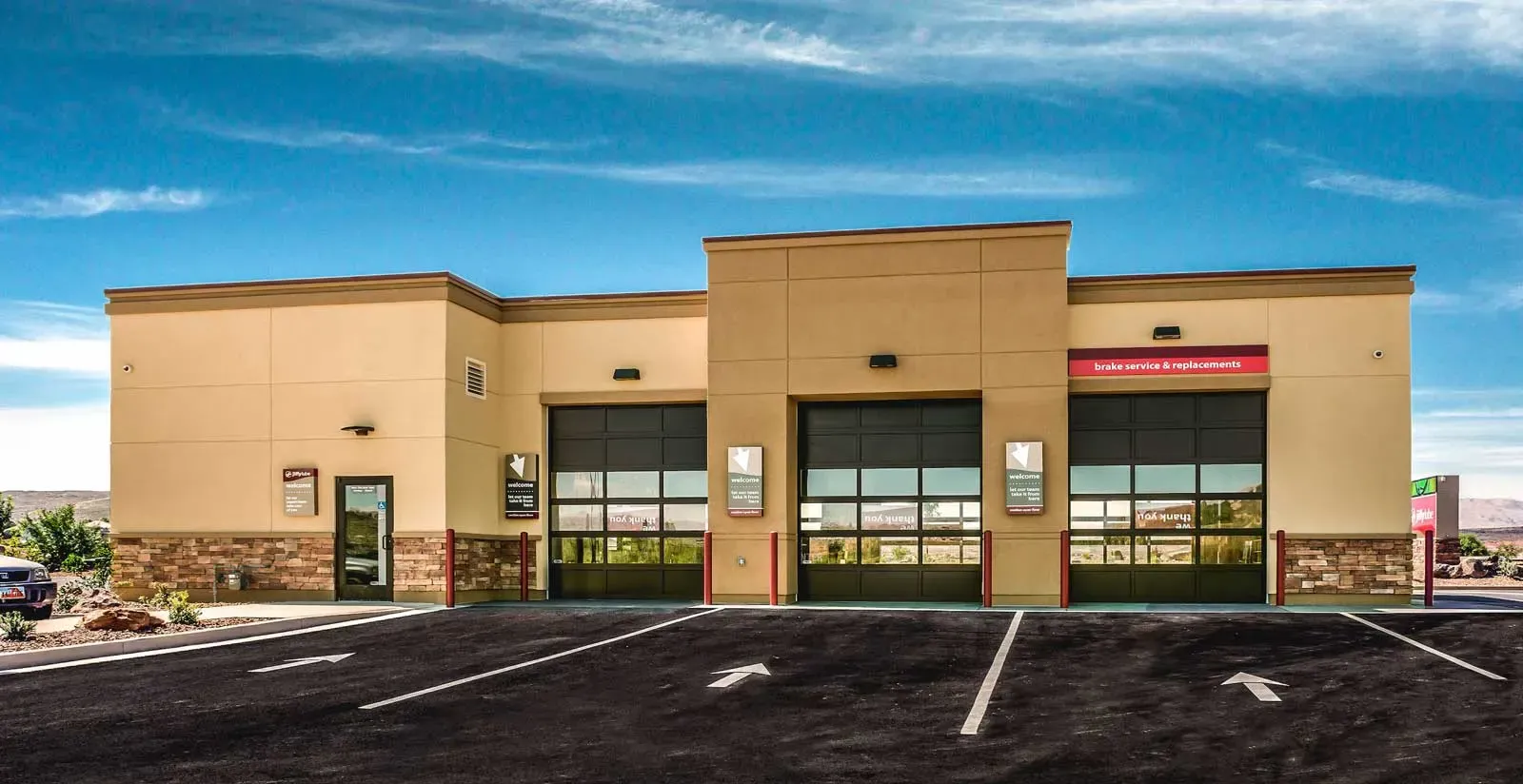 Side of the building with three overhead service bay doors and a row of parking stalls.