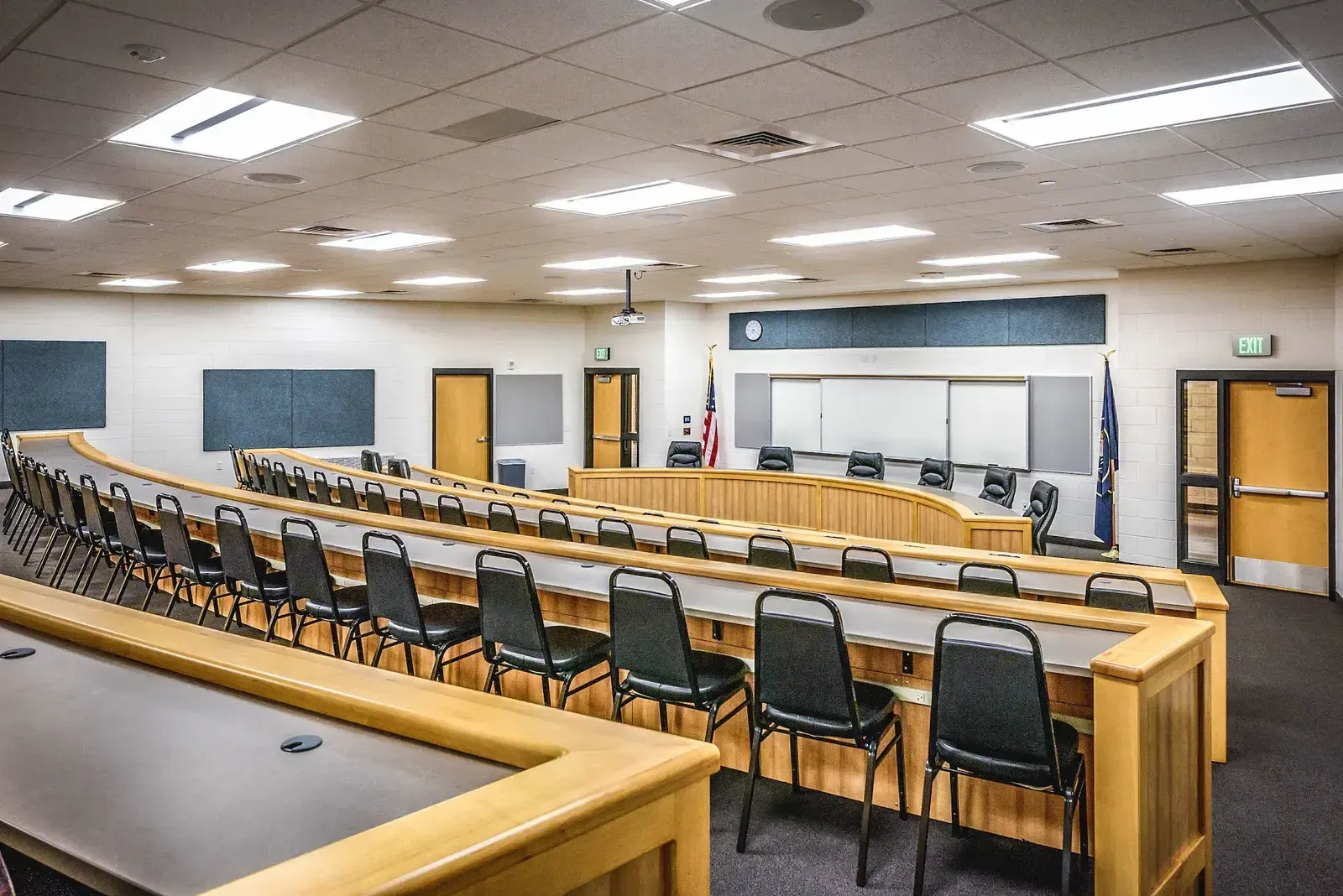 Tiered classroom with curved wood desks and black chairs.