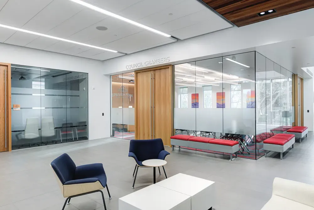 Lobby outside the glass-walled Council Chambers, with lounge chairs and red bench seating