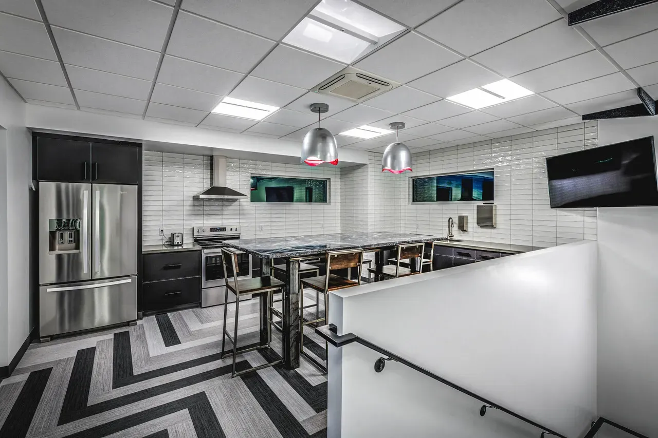 Break room with a kitchen island, stools and a herringbone-pattern floor