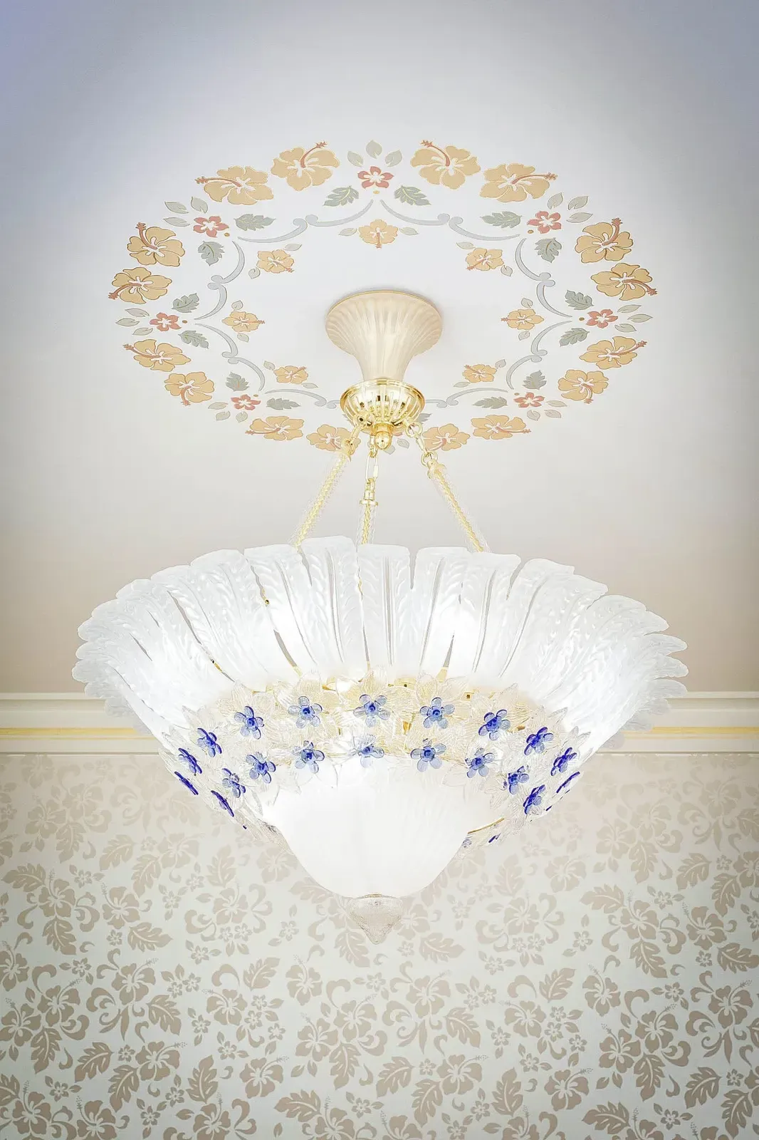 Glass ceiling light fixture with blue flowers beneath a painted flower medallion.