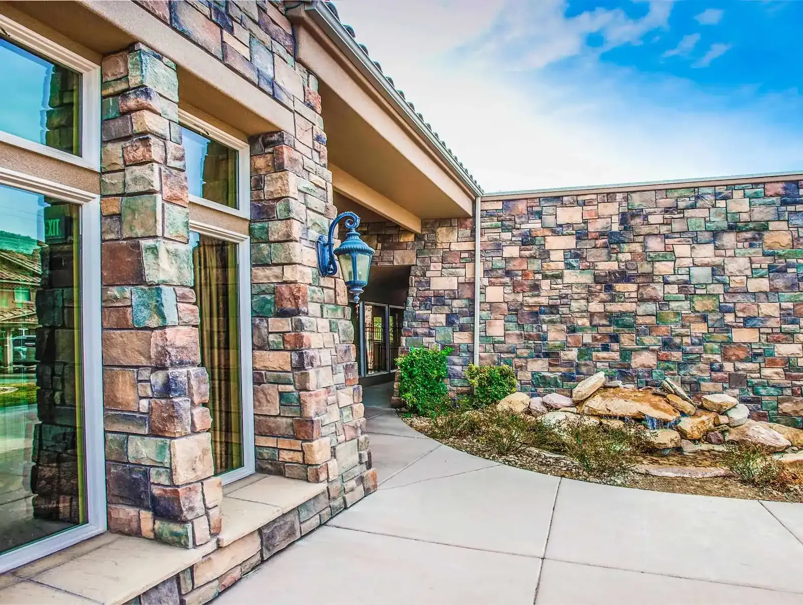 Stone-clad clubhouse entrance walkway with large windows and a decorative lantern