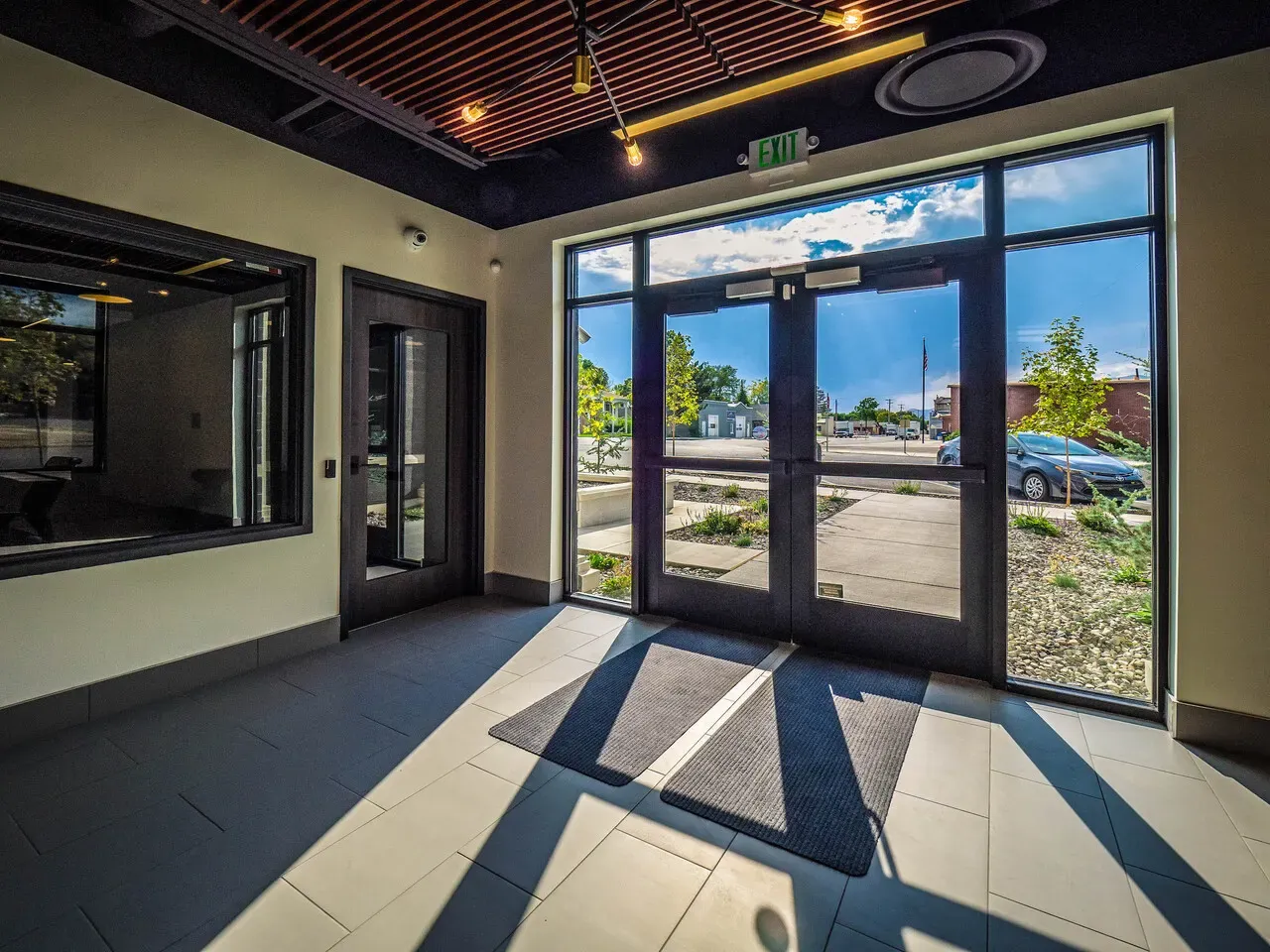 Entry vestibule with glass double doors, tile floor, and a window into an adjoining room