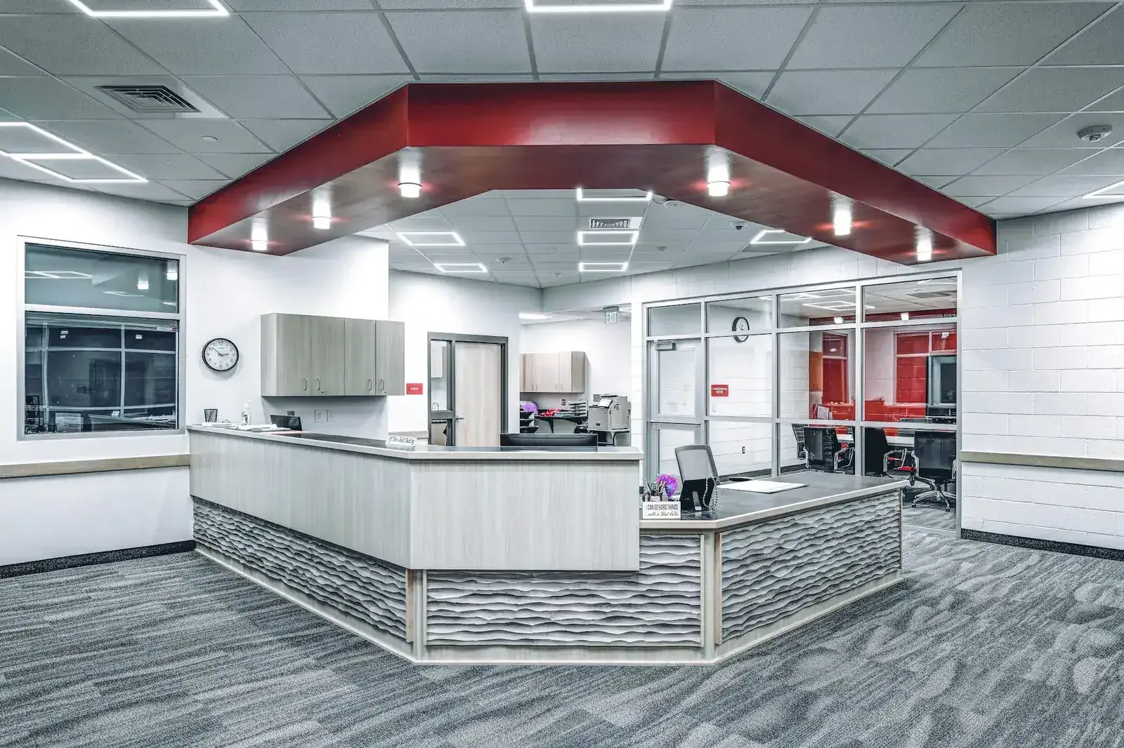 Front office with a curved reception desk and a red soffit overhead