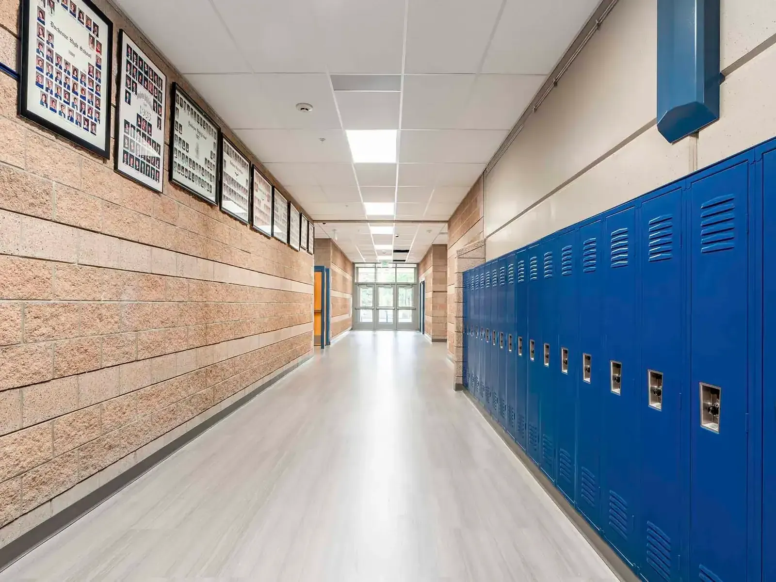 Hallway with stone-faced walls, framed class photos, and blue lockers