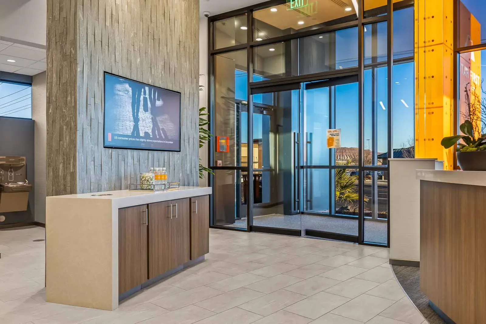 Entry vestibule with glass doors, a stone-textured column with a wall screen and a wood counter.