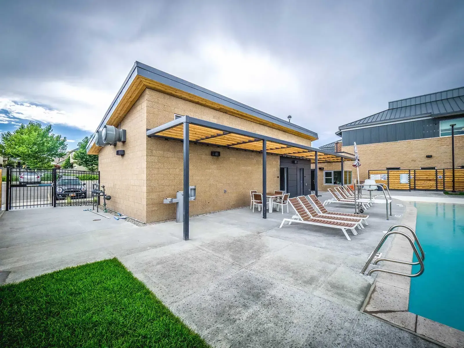 Pool building with a pergola, lounge chairs and the pool deck.