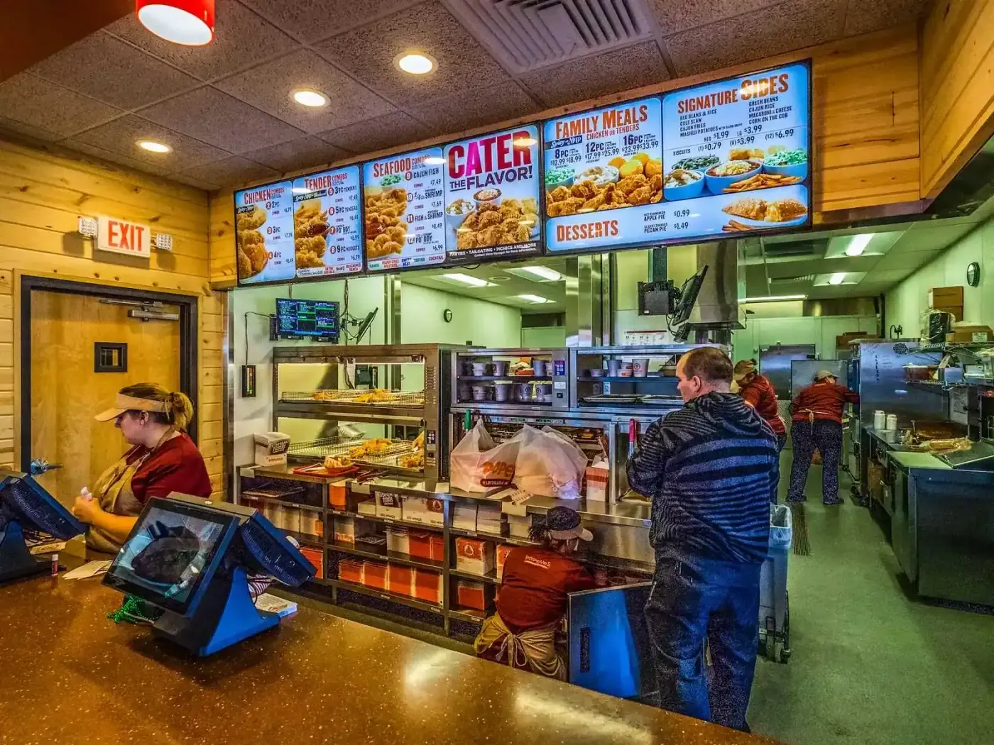 Order counter with point-of-sale screens and menu boards above the kitchen line.