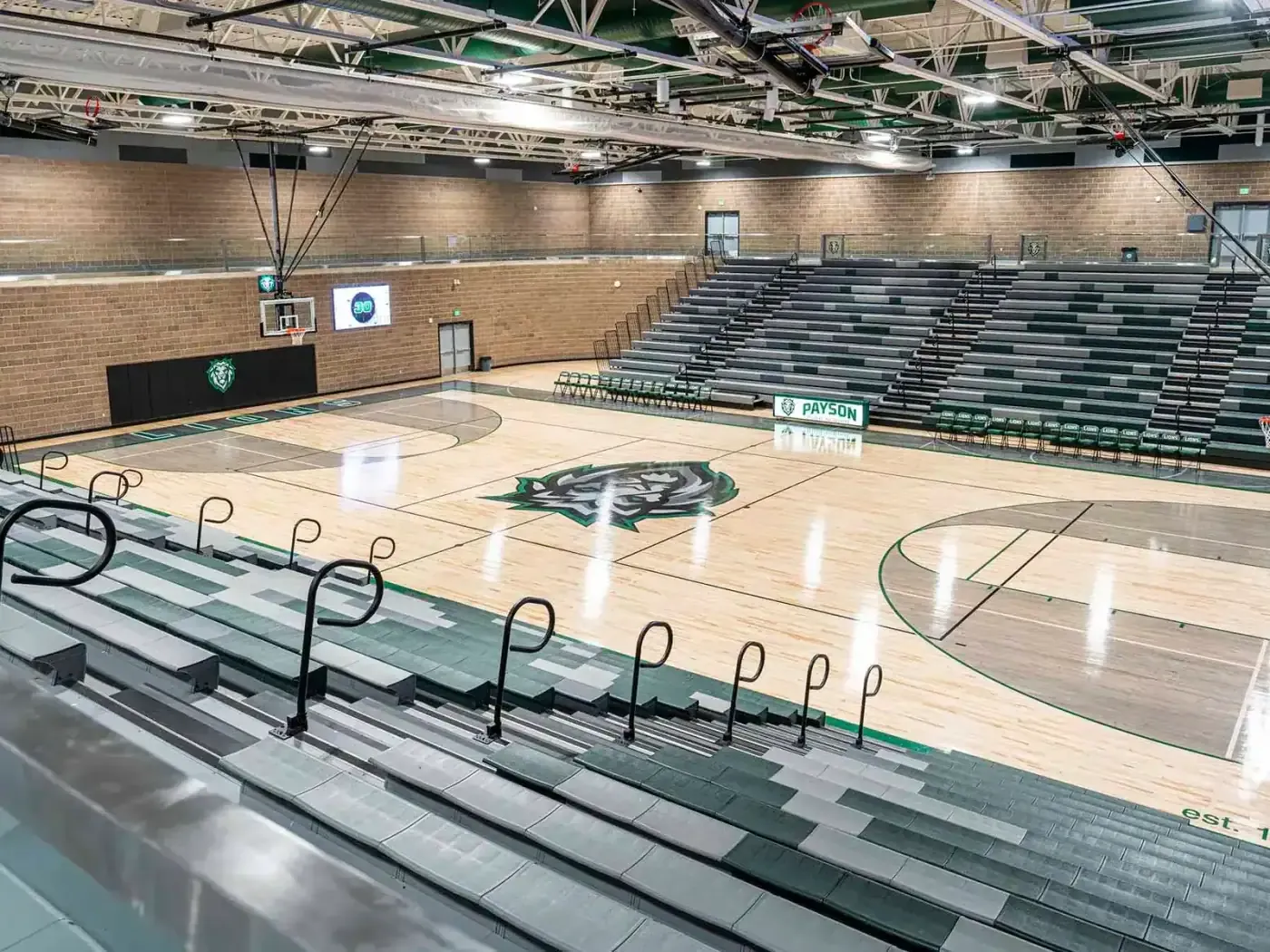 Gymnasium with a wood floor, a lion logo at center court and bleacher seating on both sides