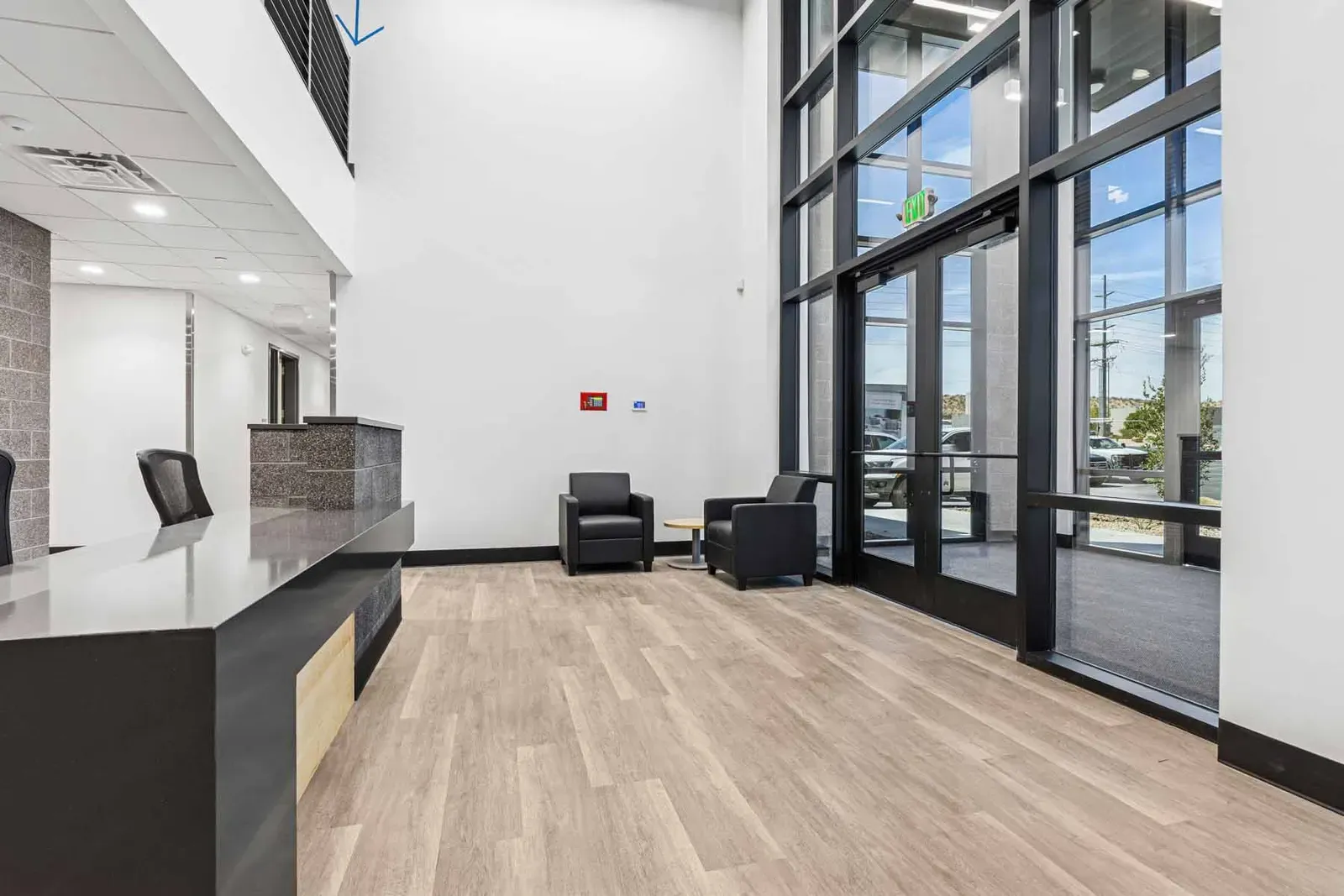 Lobby with a reception desk, two armchairs and a tall glass entry wall.