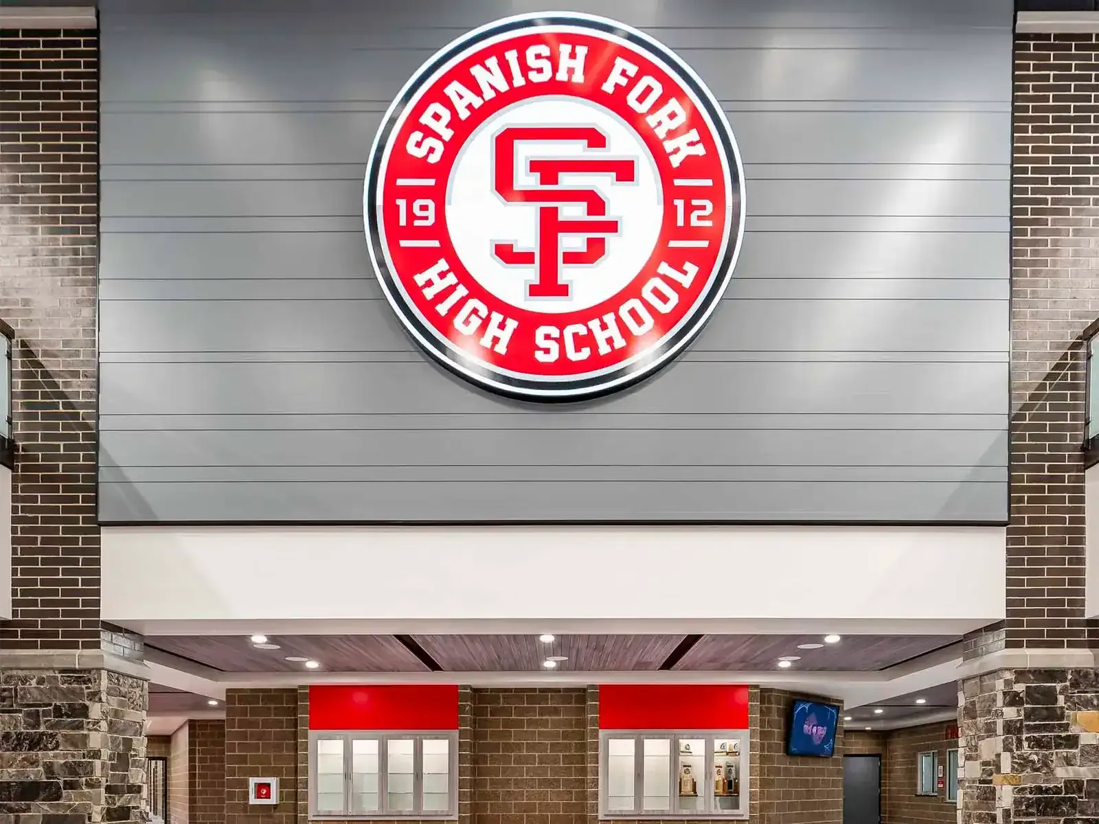 Round red Spanish Fork High School seal mounted on a gray wall above the commons.