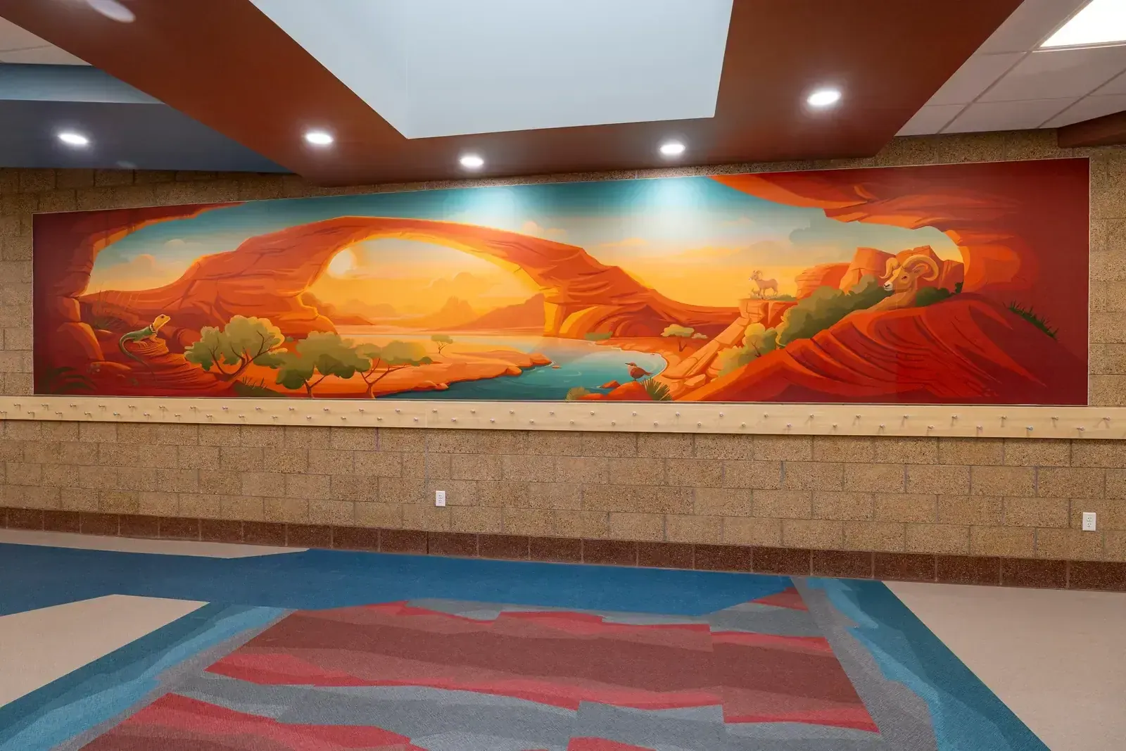 Painted desert mural of a natural stone arch over water, above a patterned red and blue floor.