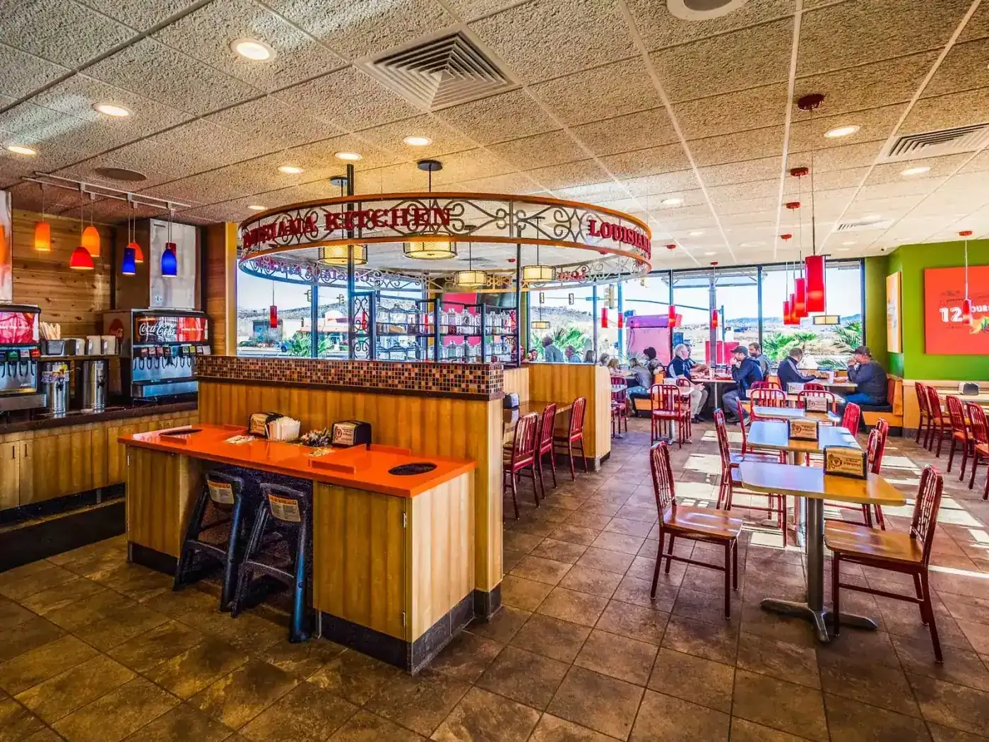 Wide view of the dining room with wood booths, tables, red chairs and the ring-shaped sign.