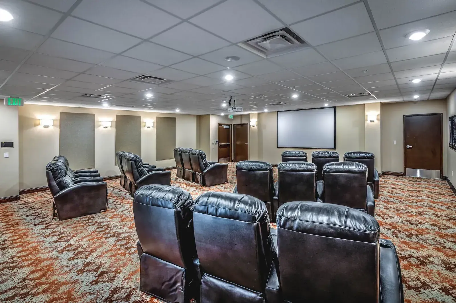 Theater room with rows of leather recliners facing a projection screen.