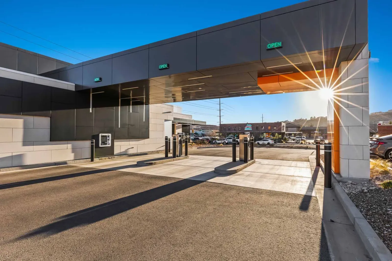 Drive-up lanes under a dark metal-panel canopy, with bollards and a drive-up service unit.