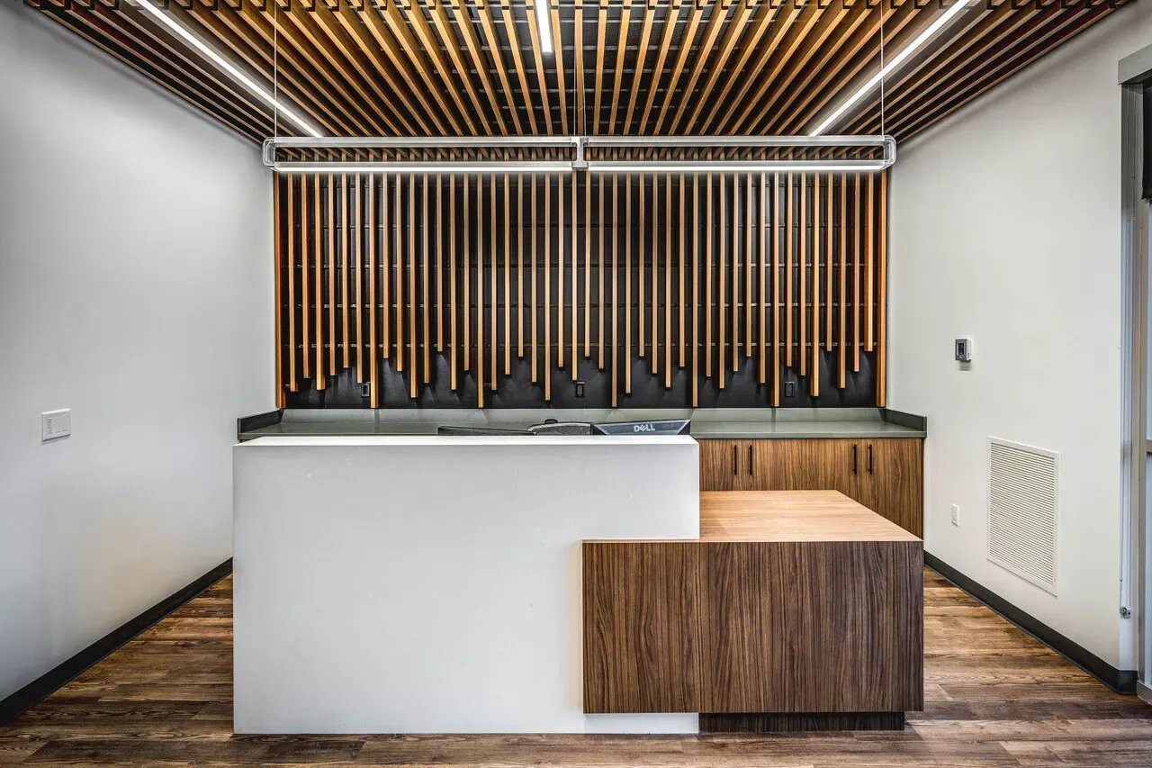 Reception desk in front of a wall of vertical wood slats under a wood-slat ceiling