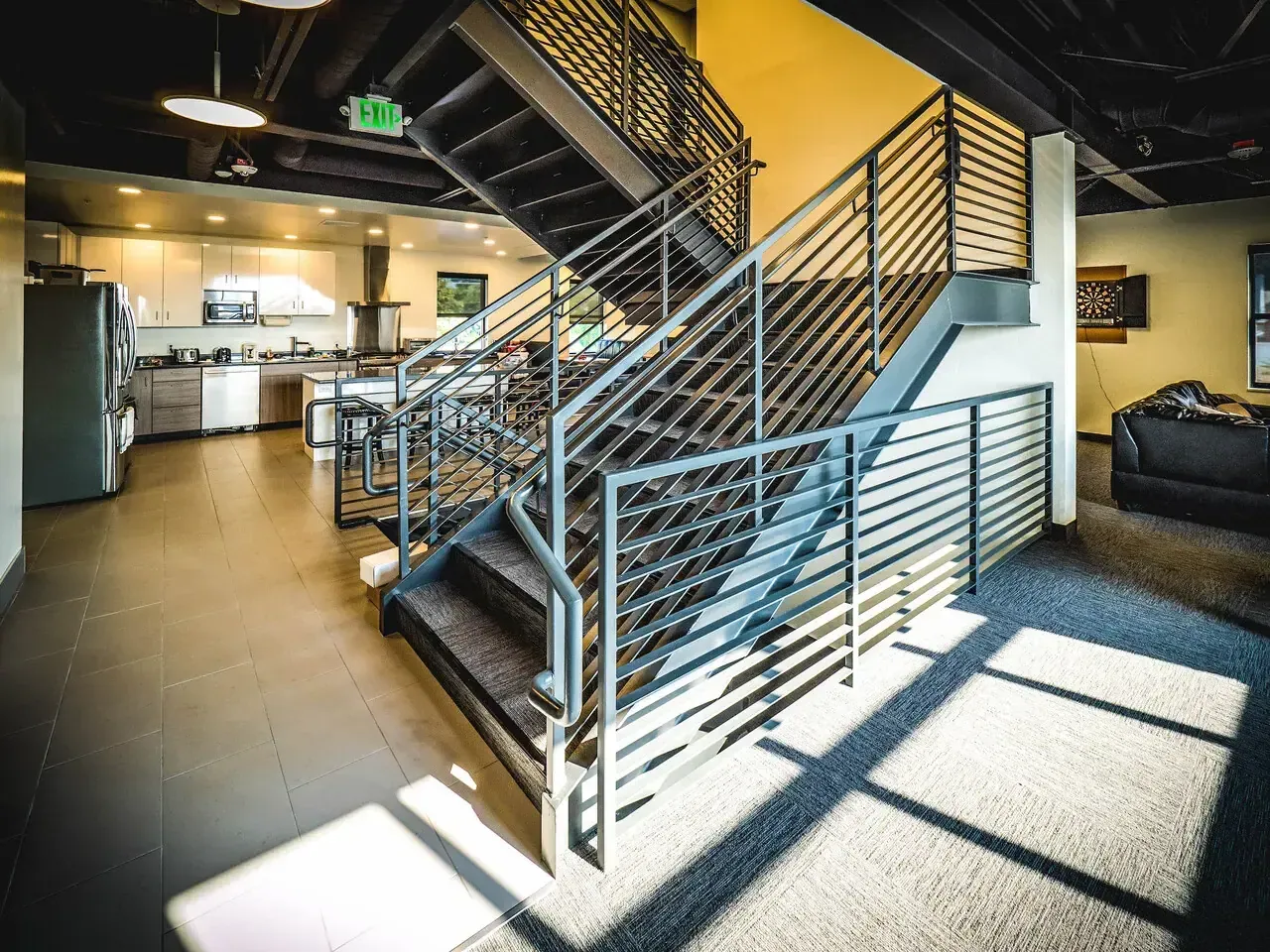 Open steel staircase with horizontal-bar railings beside the kitchen
