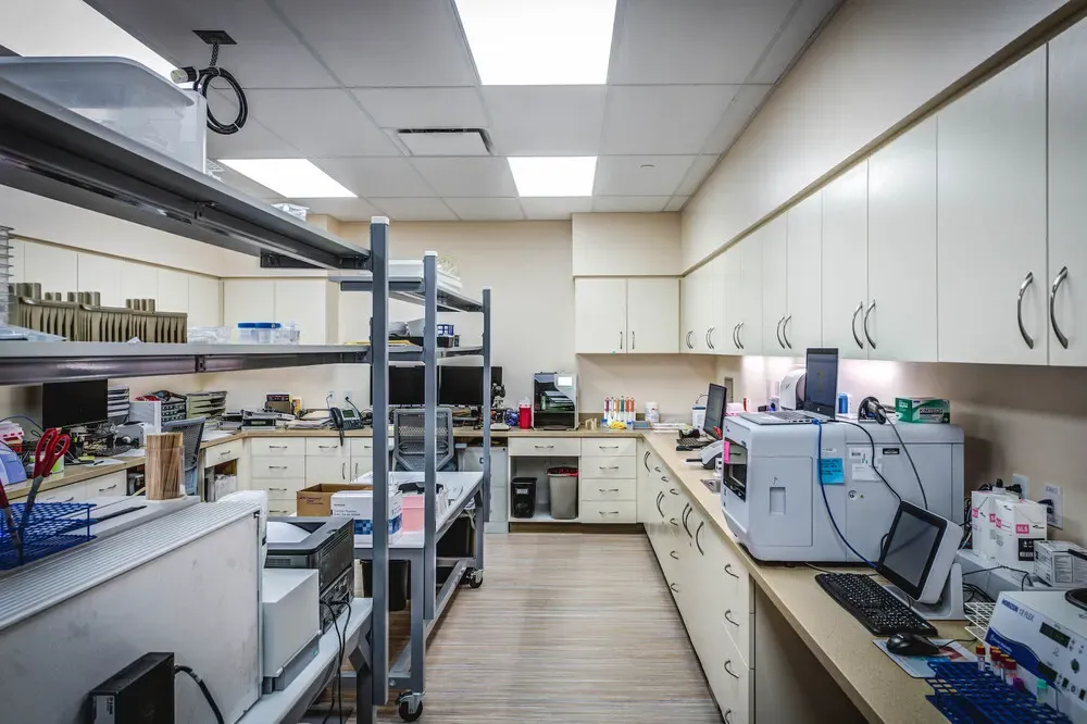 Laboratory workroom with open shelving, countertop instruments and white cabinets