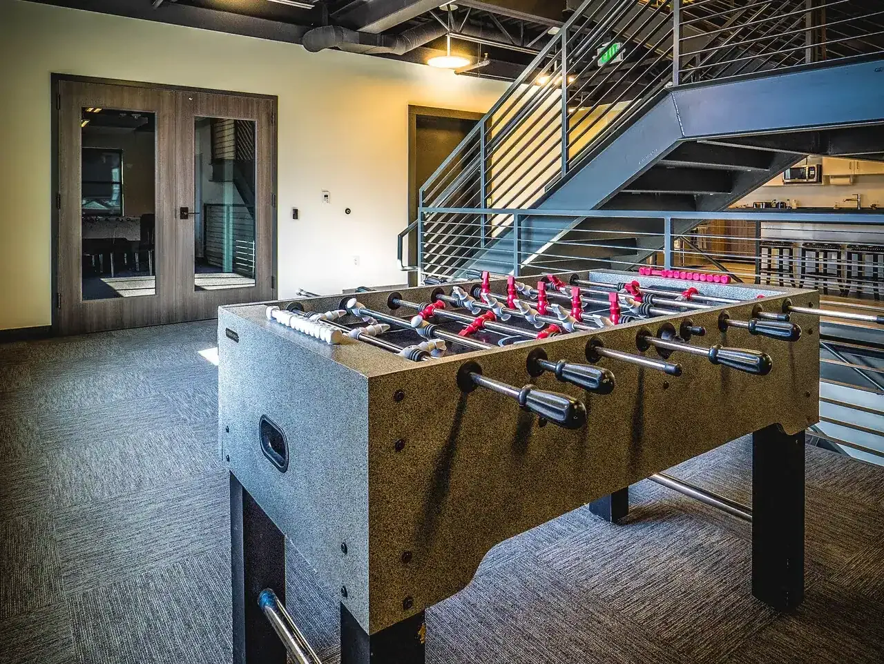 Foosball table in the stair area with the open steel staircase behind it