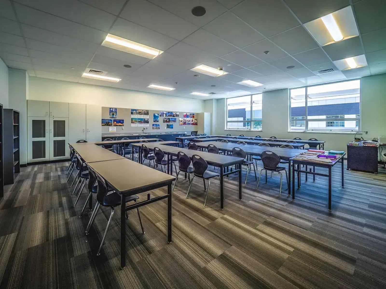 Classroom with long tables and chairs, wall displays and windows