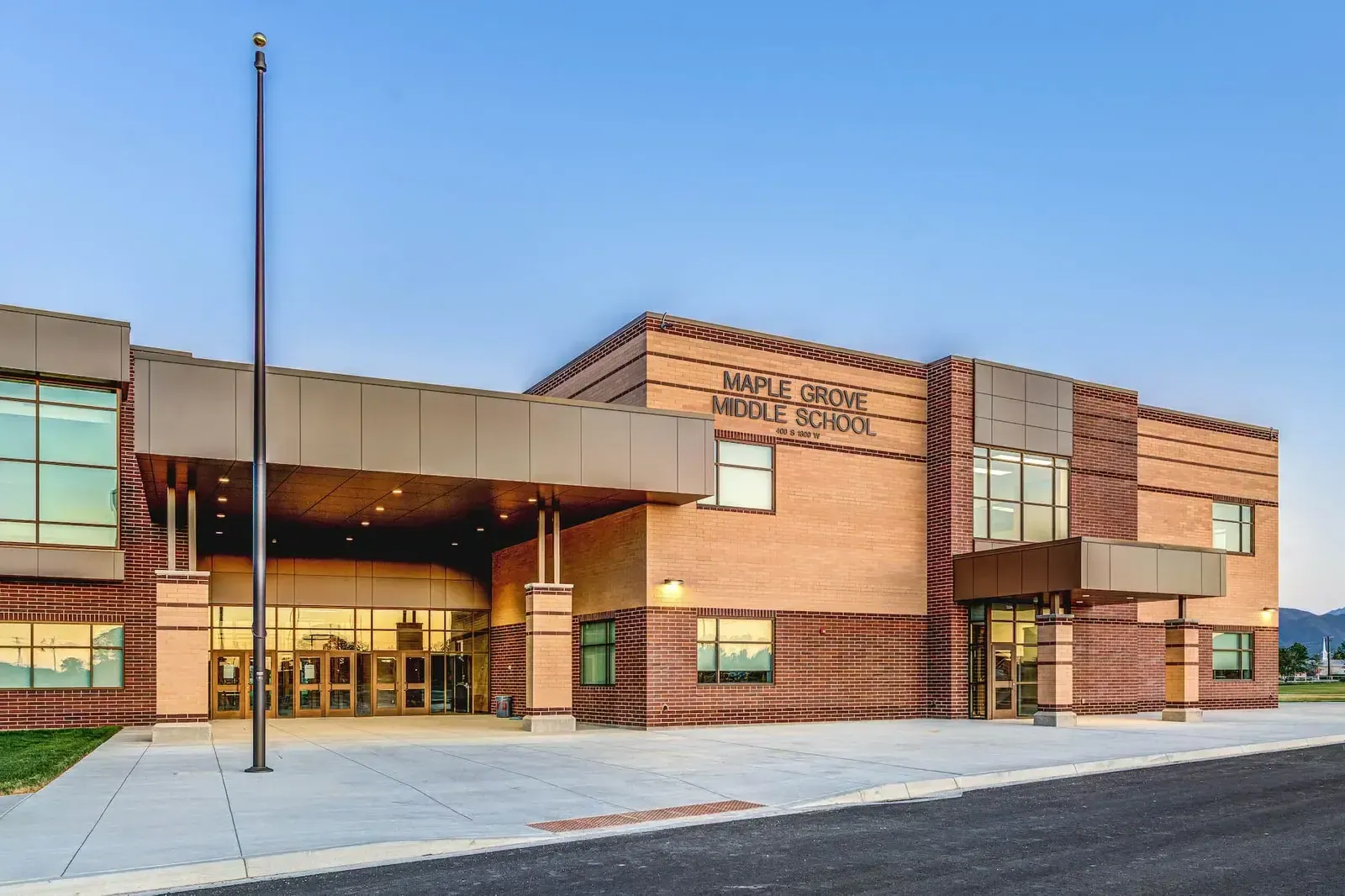 Main entrance of Maple Grove Middle School with a covered canopy, brick walls and the school name on the building.