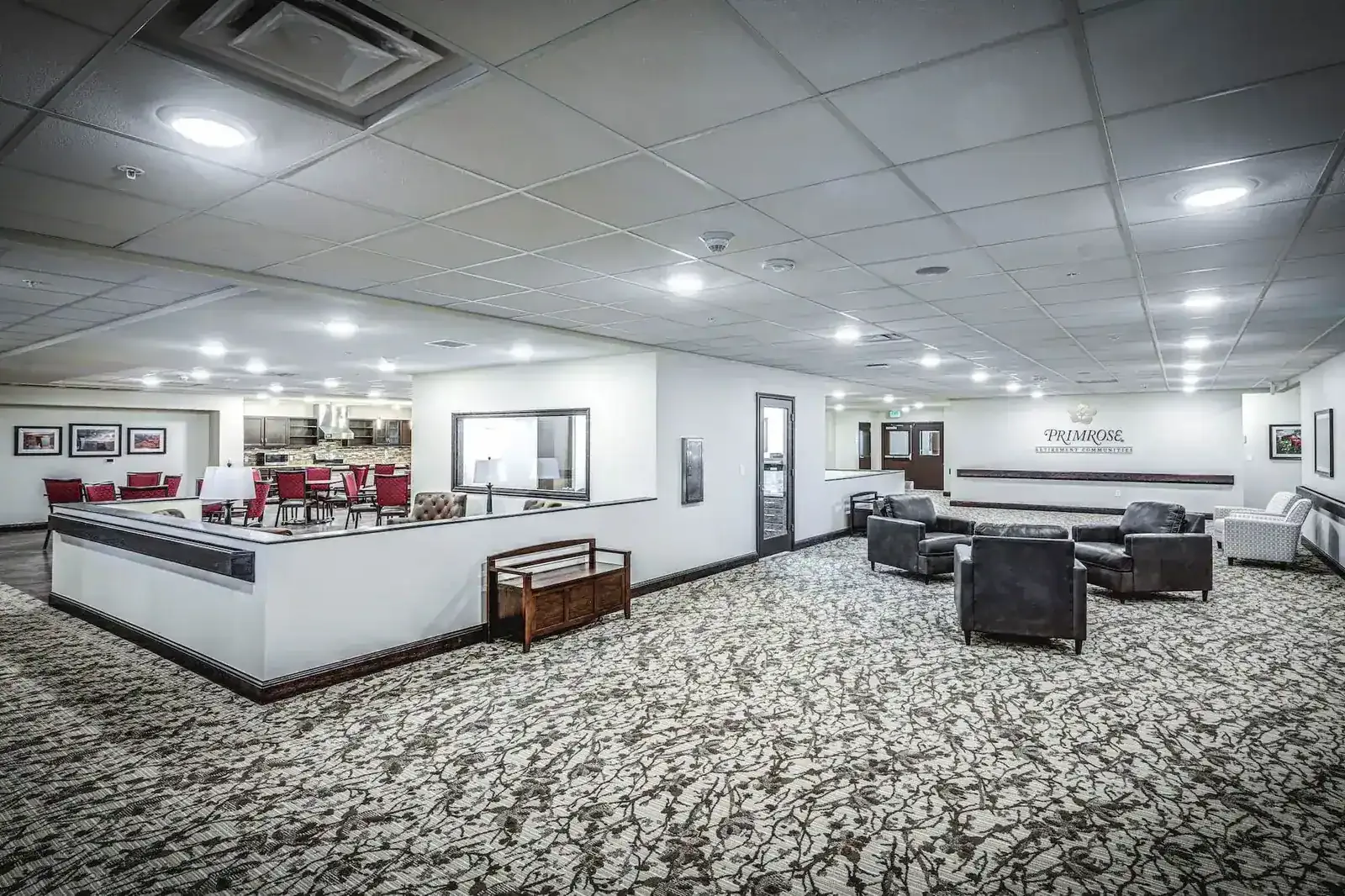 Open lounge with sofas and armchairs, a half-wall counter and a Primrose sign on the far wall.