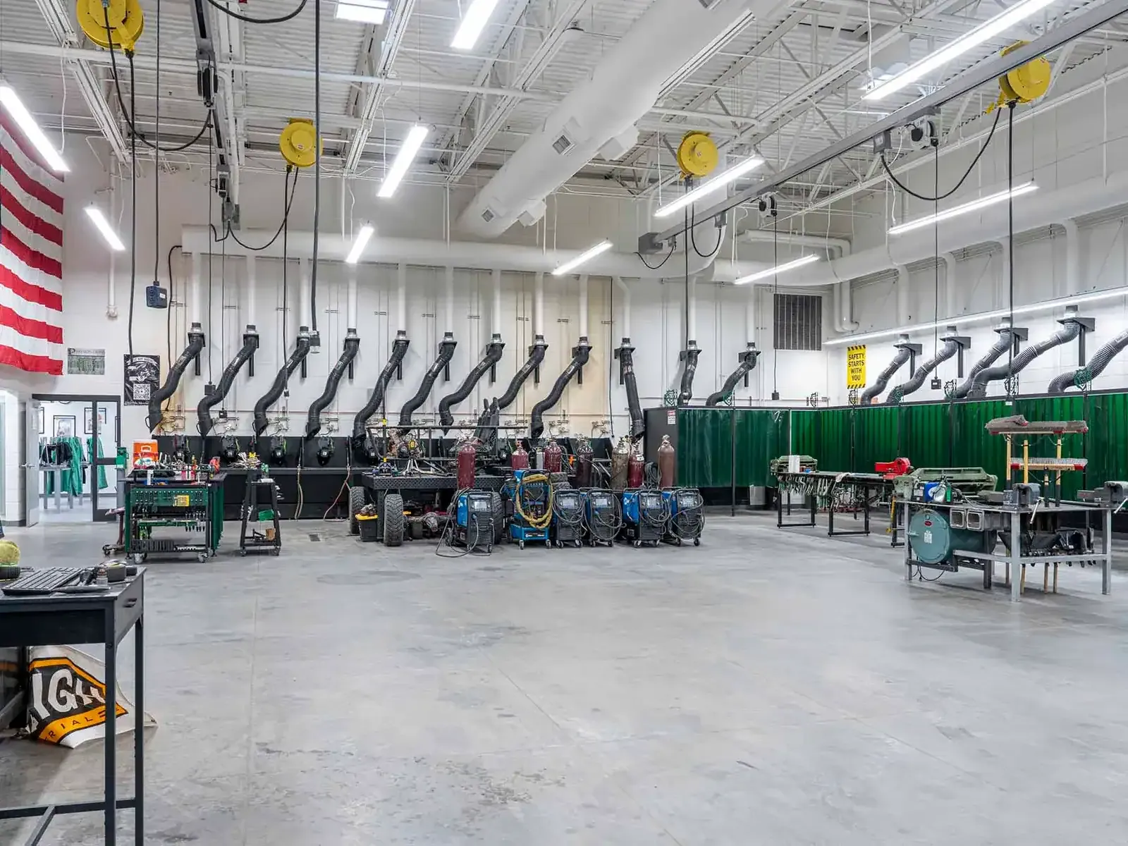 Welding shop with overhead fume extraction arms and welding stations