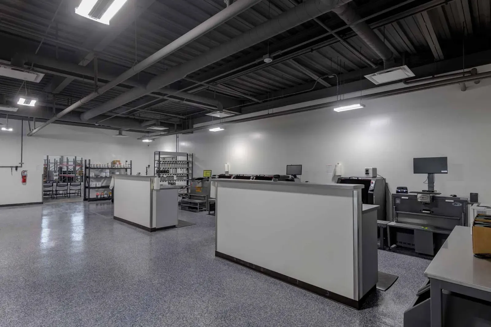 Back-of-house work area with partition counters, computer stations, and shelving on a speckled floor