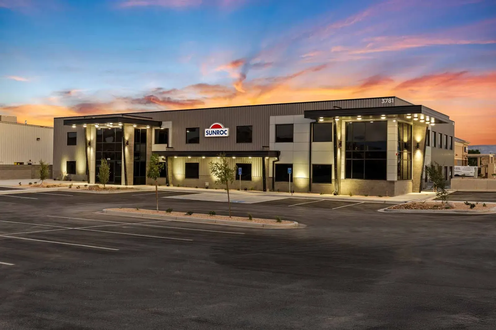 Front of the office building at dusk with a Sunroc sign and an empty parking lot.
