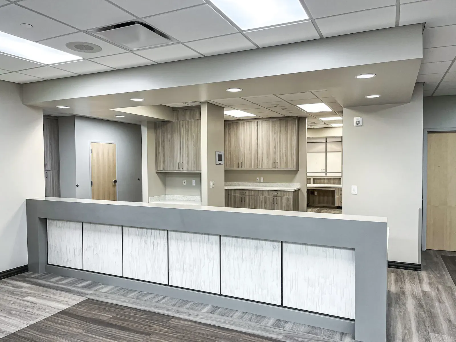 Reception counter with wood-look cabinets and a doorway behind it