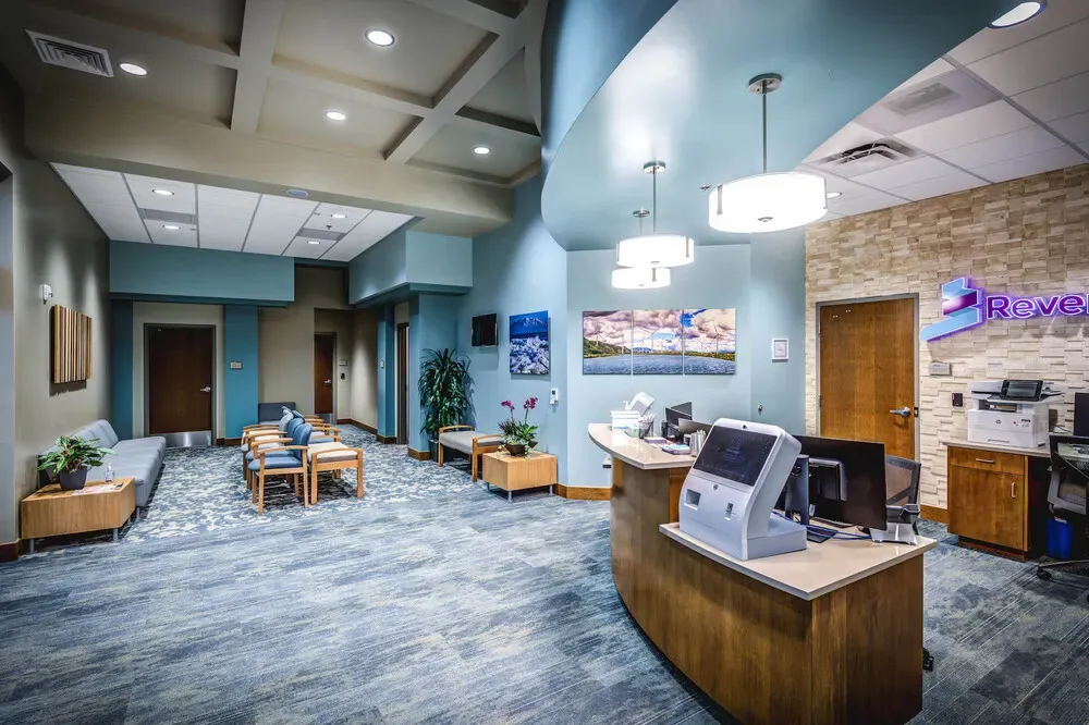 Reception desk and waiting area with a stone accent wall and Revere Health sign.