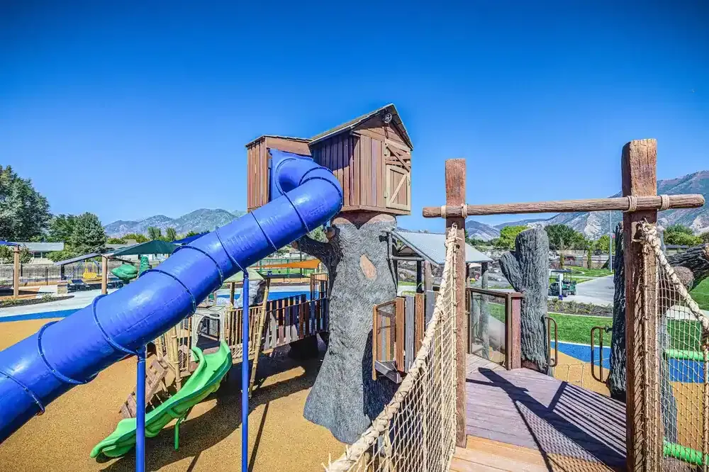 Treehouse-style play tower with a blue tube slide, a green slide and a rope bridge