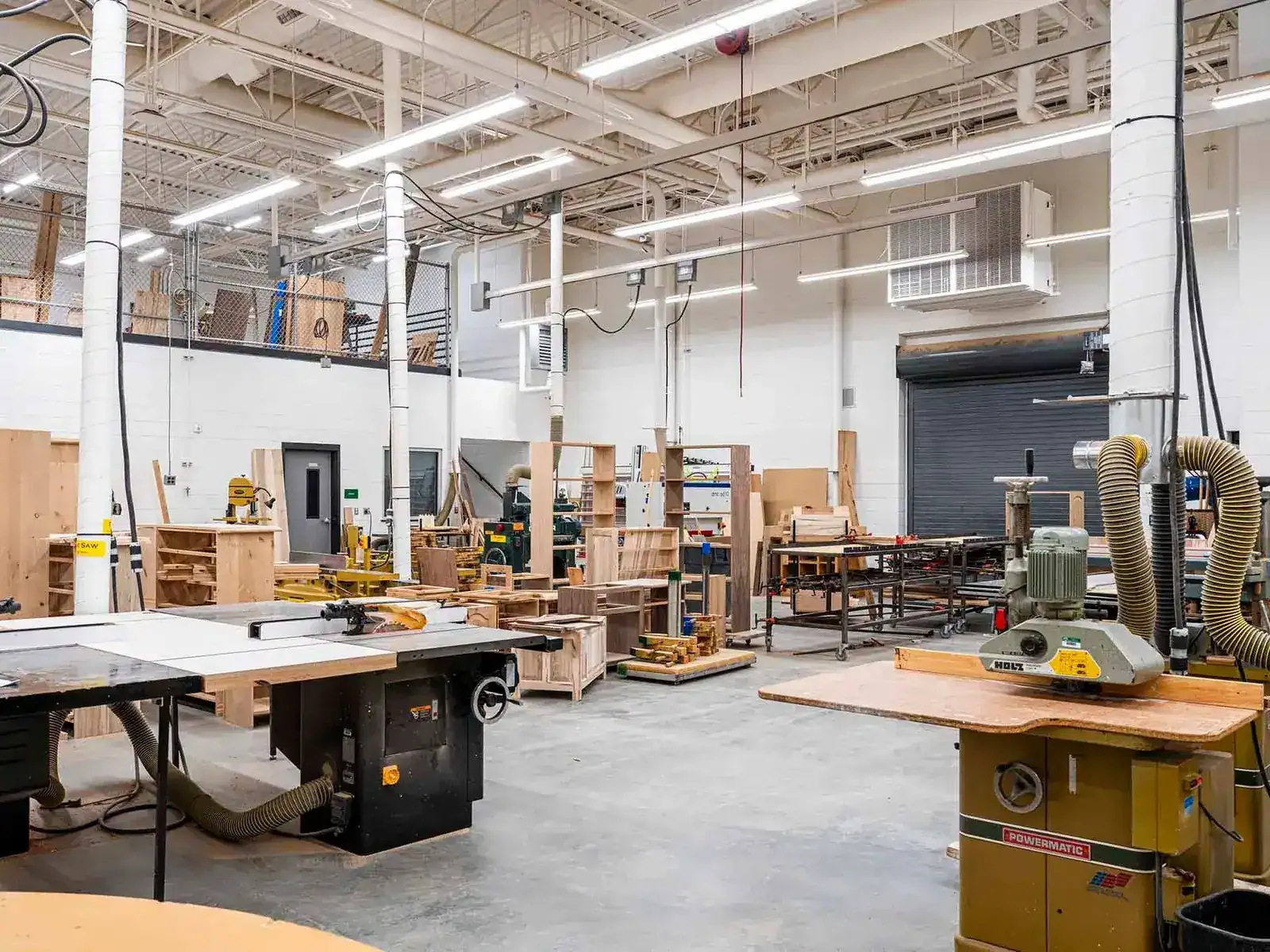 Woodshop with table saws, a shaper and wood storage racks