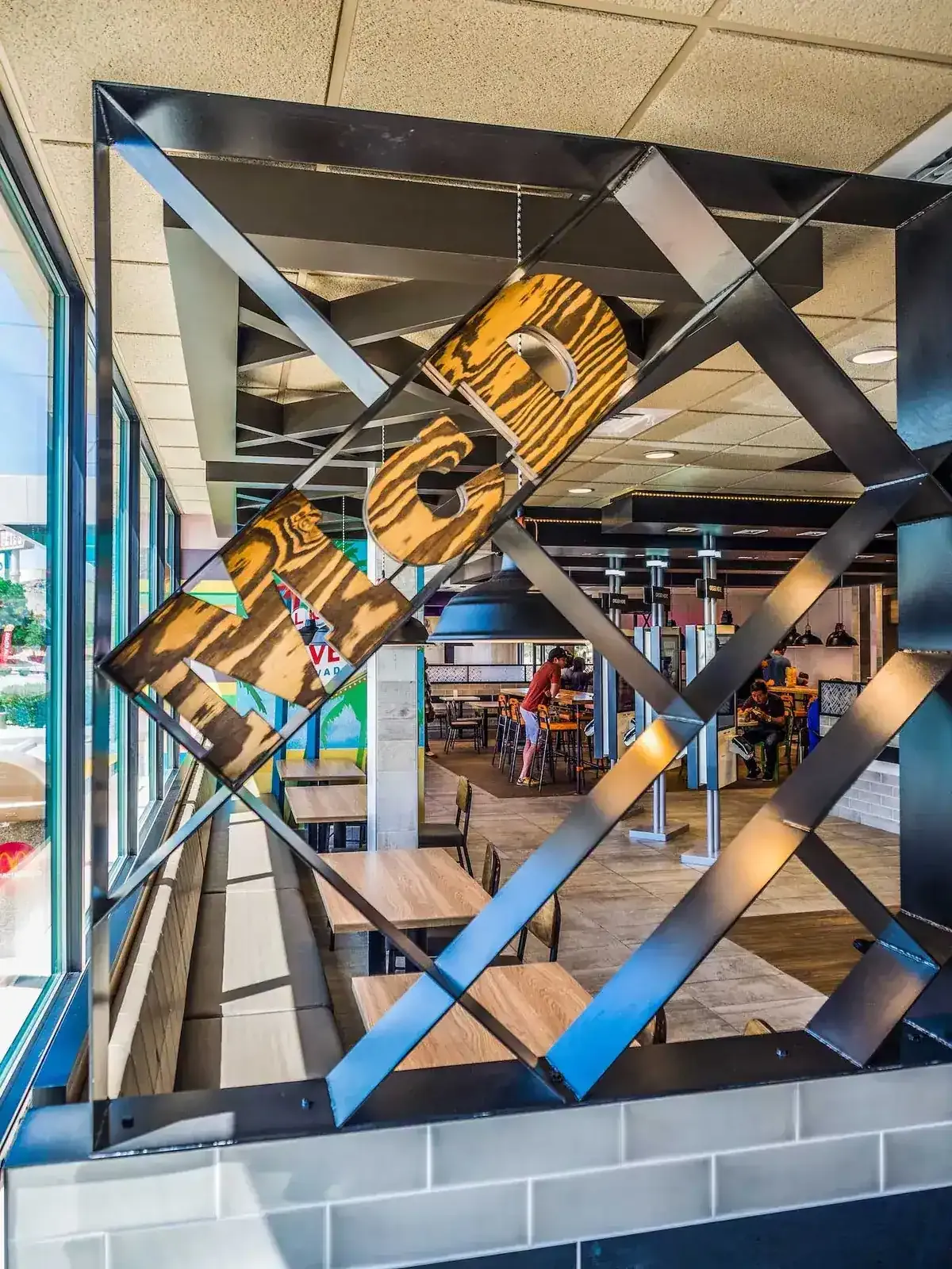 Steel diamond-pattern partition holding a large wooden sign beside the front windows.