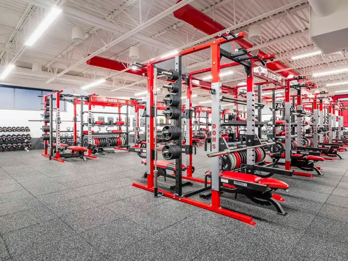 Weight room with red power racks, benches, and weight plates on a rubber floor.