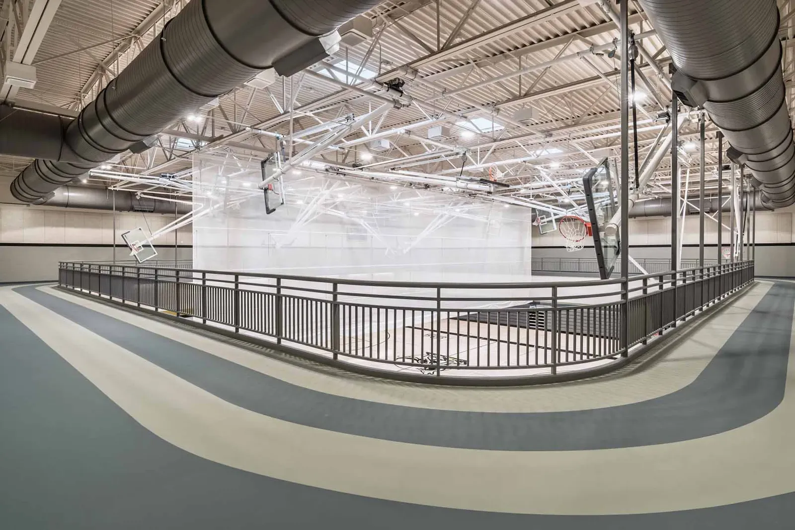 Indoor running track curving around the gym under a high steel-framed ceiling.