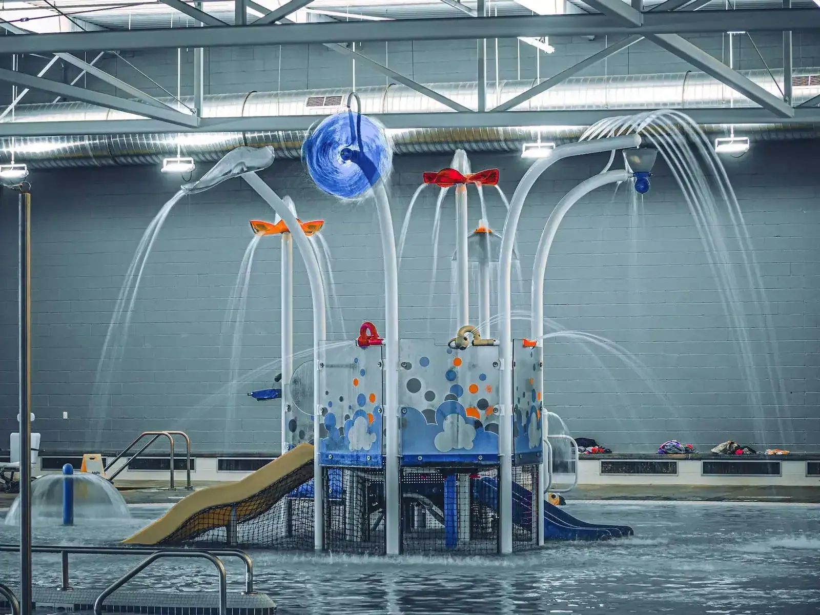 Water play structure with spray arms and a slide in the recreation pool area.