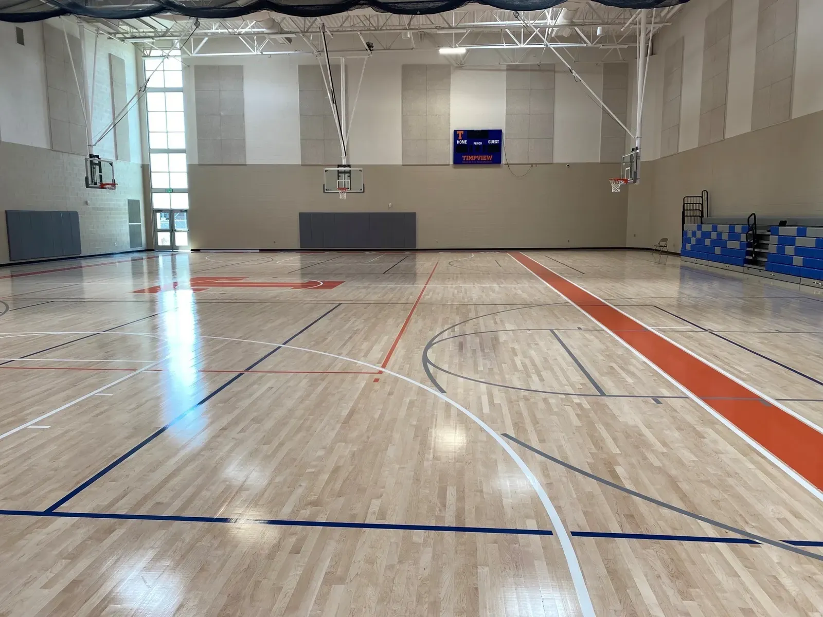 Gymnasium with a wood floor, orange court lines, hoops and a Timpview scoreboard.