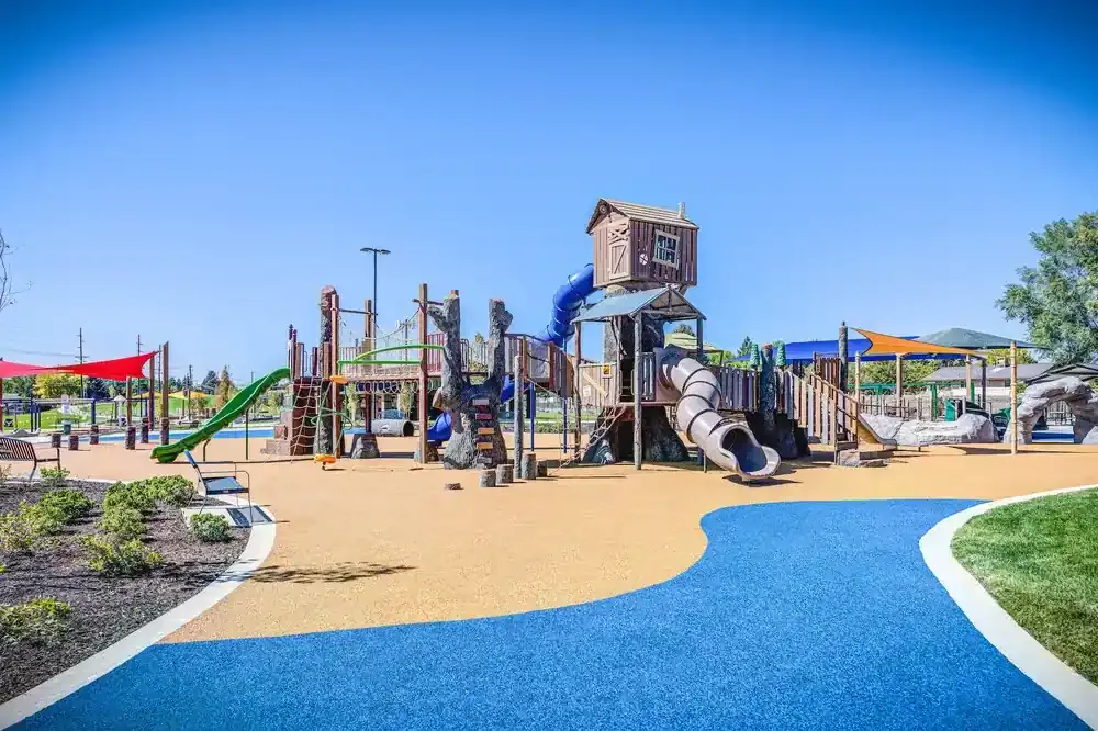 Large wooden-themed play structure with slides and towers on a blue and tan rubber surface