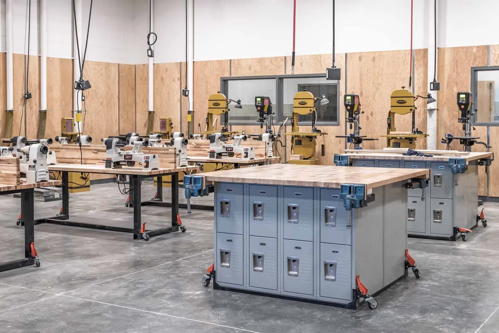 Woodshop with workbenches, tool cabinets and rows of woodworking machines.