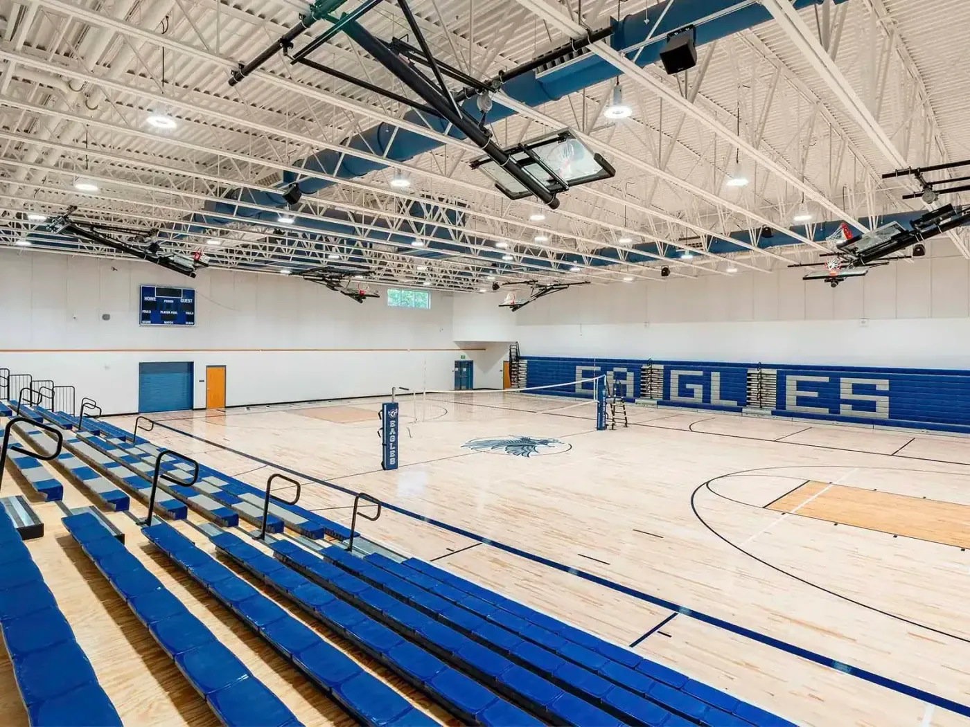 Second gymnasium with blue bleachers, a wood floor, and "EAGLES" lettered on the wall