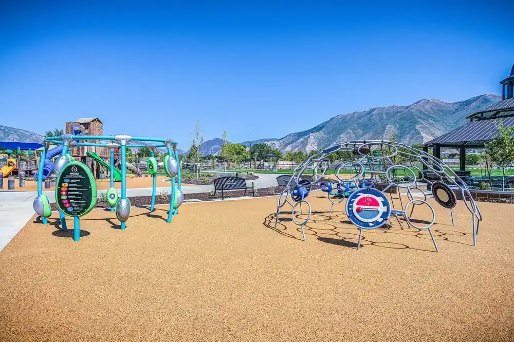 Spinning and climbing play equipment on a rubber surface with mountains behind