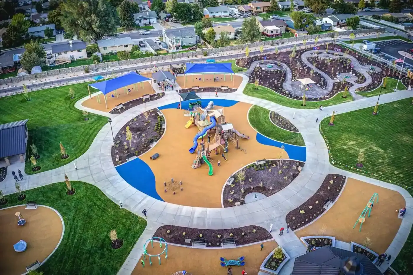 Aerial view of a circular path around playground areas, shade structures and planting beds