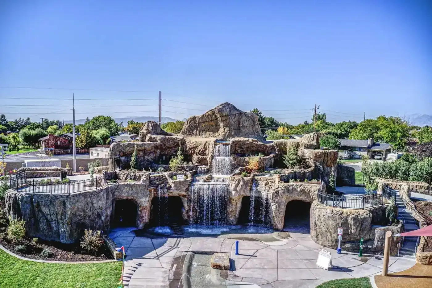 Rock waterfall feature with cave openings and railings above the splash area, seen from above